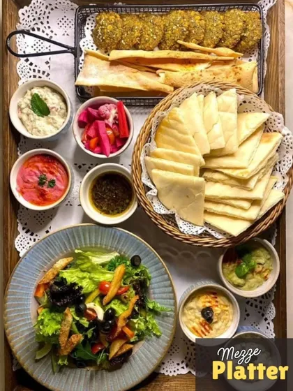 My classic Mezze Platter is a journey to the Mediterranean. It includes creamy, homemade hummus and other dips, crispy falafel, pickled vegetables, fresh salad, and warm pita bread, all arranged and ready to serve.