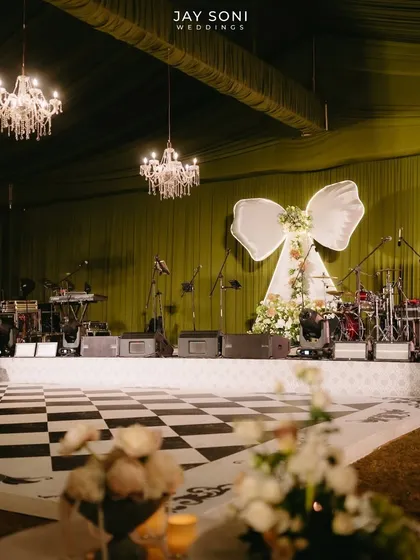 A full view of the stage setup, including the checkered dance floor, showing how all the elements from the chandeliers to the bow backdrop come together for a cohesive and stylish event.