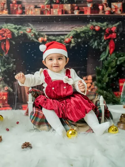 A sweet, smiling portrait of the baby girl sitting amidst the festive decorations.