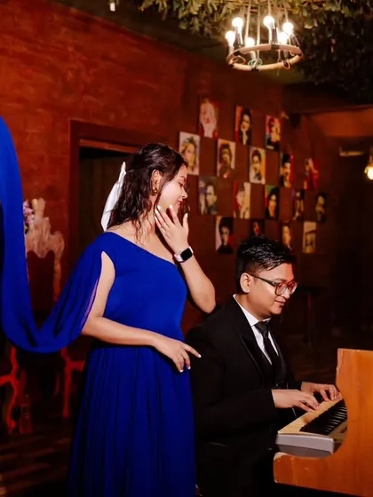 The flowing blue dress creates a sense of motion and drama as the groom plays the piano. This is a great example of a creative and dynamic pre-wedding photo.