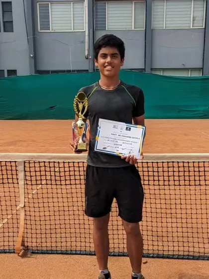 Rohit proudly displays his U14 Championship Series singles trophy on the court.