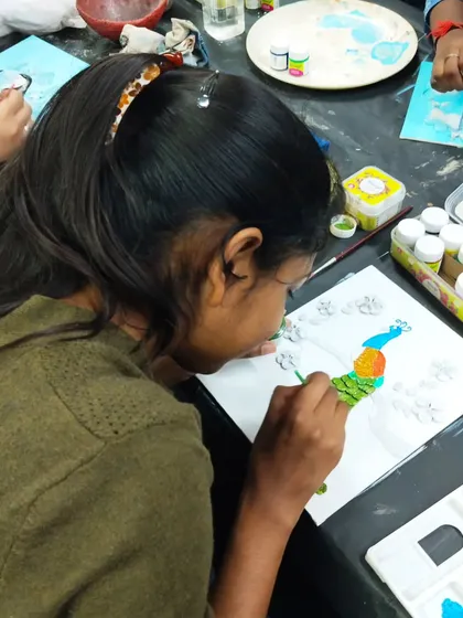A student painting a peacock design during our "Blue Paradise" workshop, which focuses on clay and mouldit-based crafts.