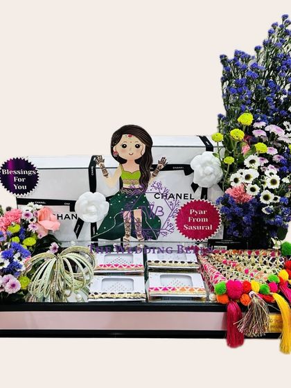 Another view of our beautiful Teej hamper, featuring a cute caricature, fresh flowers, and traditional elements like parandis.