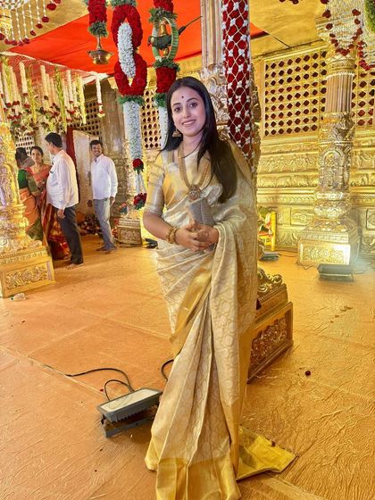 Soundarya at a wedding, surrounded by the golden glow of the venue that matches her beautiful saree.
