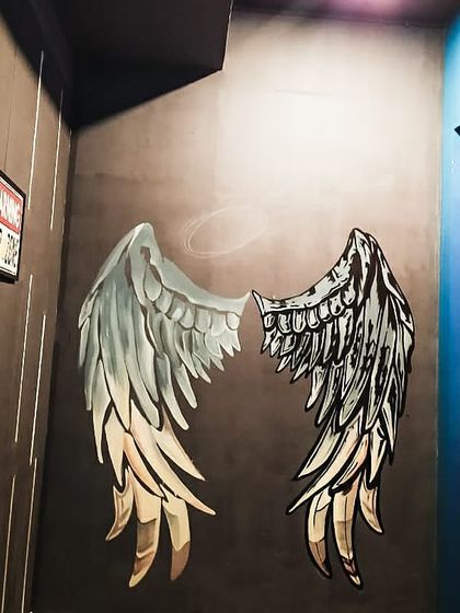 A clean shot of the finished angel wings mural at Westeros, HSR. The design uses strong black lines and subtle shading to stand out and create a 3D effect for photos.