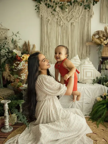 The pure joy between a mother and her child. This lifestyle portrait captures a genuine, happy moment against a soft, bohemian backdrop, celebrating the beautiful bond they share.