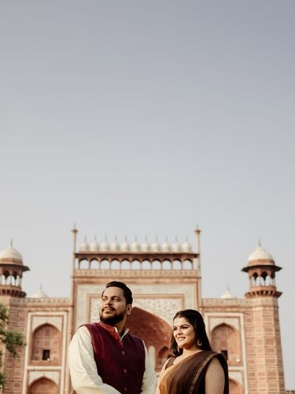 A grand portrait at the main gateway of the Taj Mahal complex. The red sandstone architecture provides a beautiful contrast and a sense of arrival.