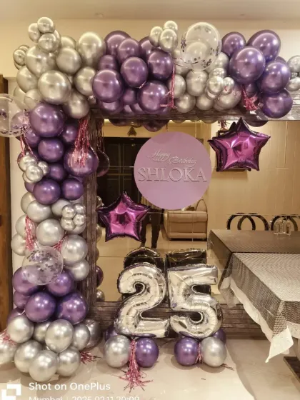 An elegant at-home decoration for a 25th birthday. We created a balloon arch with chrome silver and purple balloons, star-shaped foil balloons, and large number balloons to make the celebration feel special even in a smaller space.