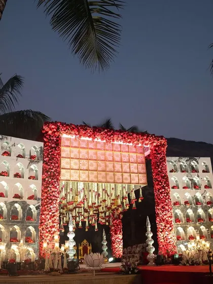 A stunning mandap design with red floral arches and hanging floral strings, creating a dramatic and romantic setting for a night wedding.