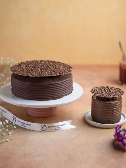 A decadent masterpiece for any occasion. This photo showcases both a large and a mini version of our rich chocolate cake, perfect for celebrations of any size.