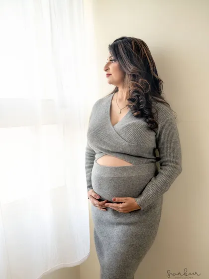 A quiet moment of reflection by the window. This portrait uses soft, natural light to create a gentle and introspective mood, highlighting the peaceful anticipation of motherhood.