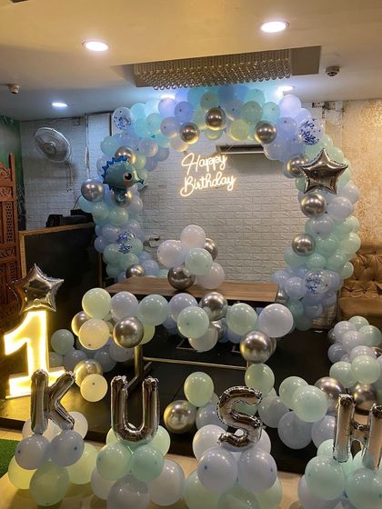 A closer look at the pastel dinosaur-themed balloon arch and the 'KUSH' letter balloons.