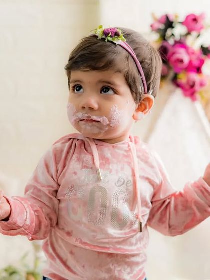 A face covered in cake is a sign of a successful party. This little one is having a wonderful time at her first birthday cake smash.