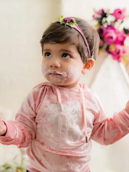A face covered in cake is a sign of a successful party. This little one is having a wonderful time at her first birthday cake smash.