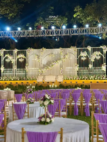Another perspective of the guest seating area, showing how the table setups and chair decor align with the overall theme of the lavender and white stage.