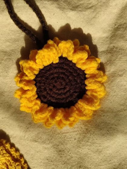 A close-up of the sunflower bag charm, showing the intricate spiral pattern of the center and the delicate petals.