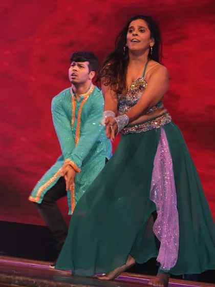An expressive shot from the same performance, capturing the emotion and energy of the dance against a rich, red backdrop.