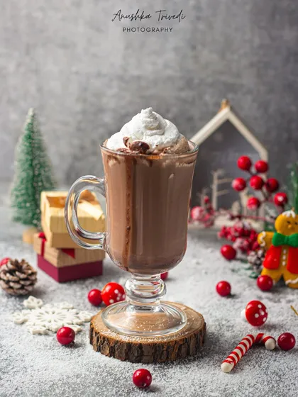 A cozy mug of hot chocolate for Christmas. The grey background and red berry props create a classic wintery scene that feels warm and inviting.