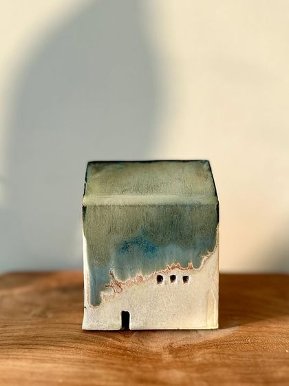 A minimalist mini house with a simple, elegant green glaze that breaks over the edges of the form.