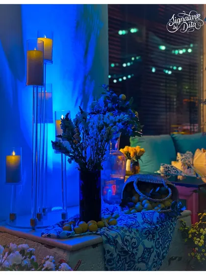 I used dramatic blue uplighting to create a cool, evening mood in this corner, contrasting with the warm glow of the pillar candles. A basket of fresh lemons adds a pop of color and fragrance.