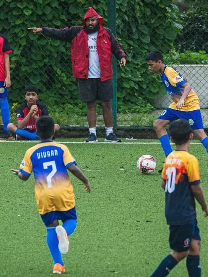 A coach gives instructions from the sideline during a U15 Thane Youth League match.