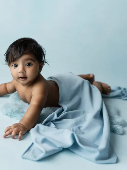 A slightly different angle, with a soft blanket draped over the baby, adding a touch of texture and coziness.