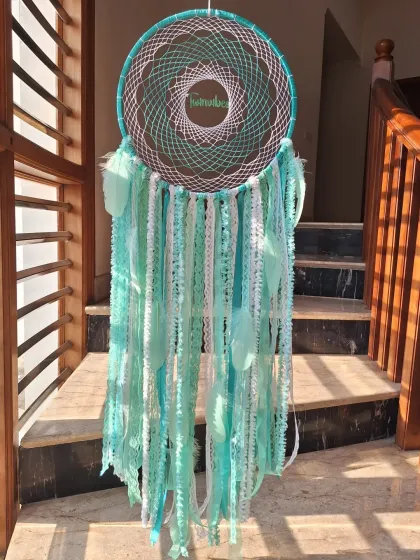 A full view of our teal green 'Twinvibes' dreamcatcher. The combination of delicate lace and soft feathers creates a beautiful texture that brings sweet dreams and peaceful nights.