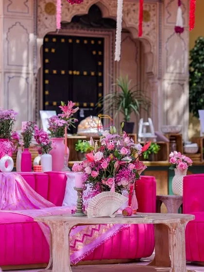 Another angle of the lounge area, highlighting the rustic wooden coffee table and the layers of pink florals against the historic palace walls.