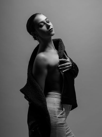 A dramatic black and white portrait with a focus on emotion. The model's pose and the strong lighting create a powerful and introspective mood.
