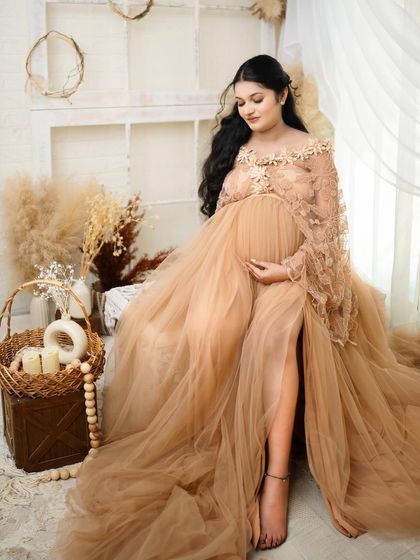 Love begins in the belly. A serene solo portrait of the mother-to-be, cradling her bump in a gorgeous lace and tulle gown, surrounded by soft, natural elements.