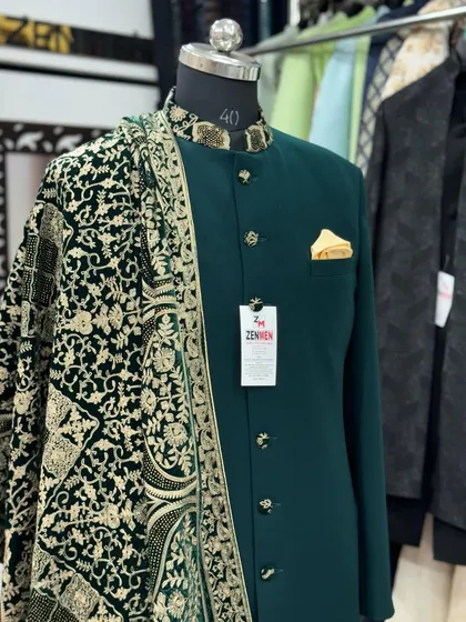 A rich, emerald green sherwani designed for a groom who wants a touch of color. The outfit is complemented by a hand-detailed velvet dupatta and a gold pocket square for a regal finish.