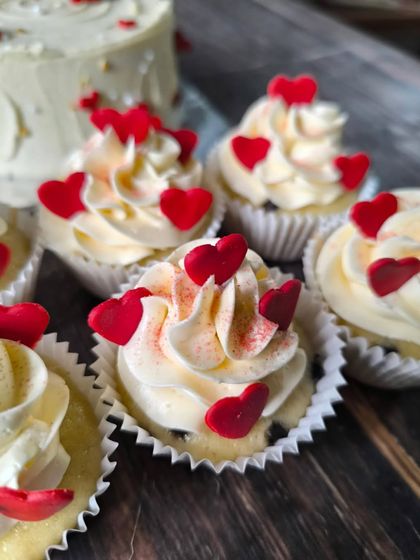 A close-up of my red heart cupcakes. I use creamy buttercream and finish them with delicate, hand-placed fondant hearts and a sprinkle of red dust for effect.
