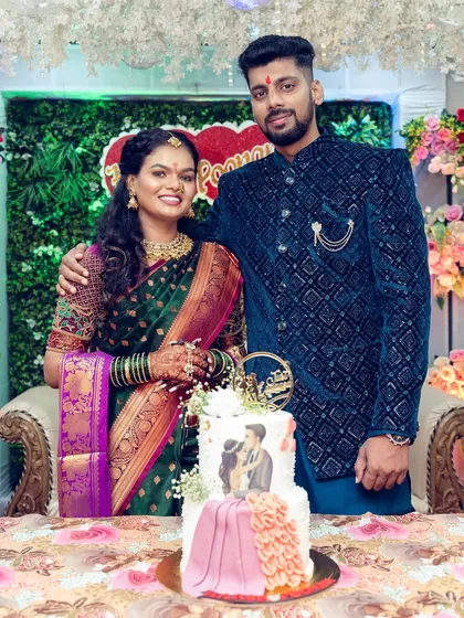The happy couple posing with their beautifully designed engagement cake, which features a custom illustration of them.