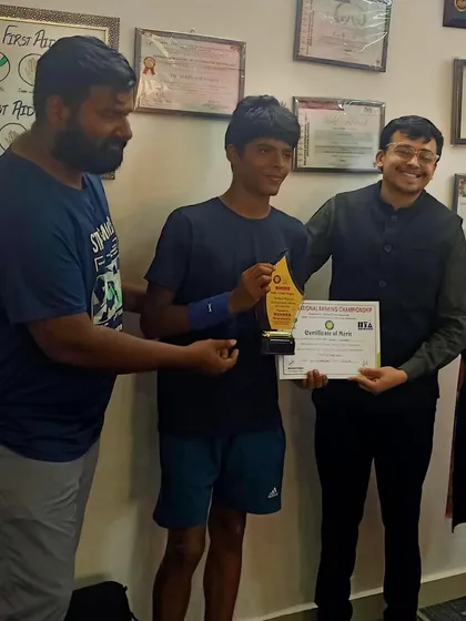 Ayush Chaudhary celebrates his first AITA National Title win with his coaches. This indoor shot captures the team's pride in his achievement as an unseeded player who beat the top seeds.