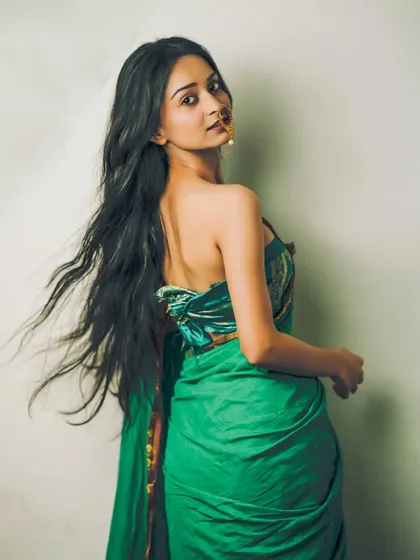 A dynamic portrait with the model's hair caught in motion, creating a beautiful contrast with the still, elegant pose in a green saree.