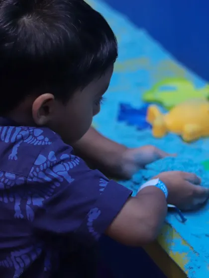 Our sand pit offers a different kind of creative play. Here, a child is focused on building and molding, enjoying a quiet moment of sensory fun.
