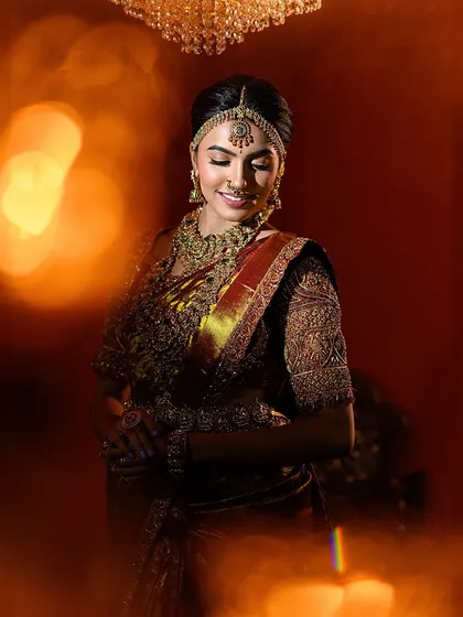 A signature Muhurtham look created for a professional makeup course, set against a warm, festive backdrop. The bokeh effect from the candle props adds a magical, celebratory glow.