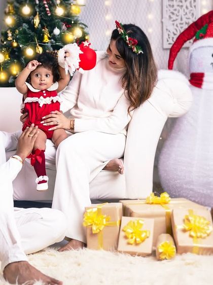 A playful moment as the parents lift their baby's Santa hat. Capturing these spontaneous interactions is key to a memorable family photoshoot.