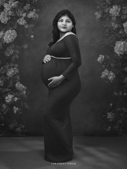 This black and white version of the floral backdrop portrait creates a vintage, almost ethereal feel. The details of the flowers and the gown are beautifully rendered.