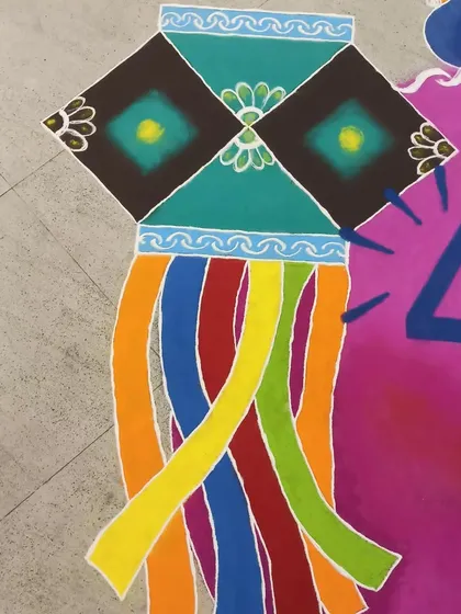A detailed view of a 'kandil' (paper lantern) from a large corporate Diwali rangoli. The geometric patterns and color gradients are all done by hand with colored powders.
