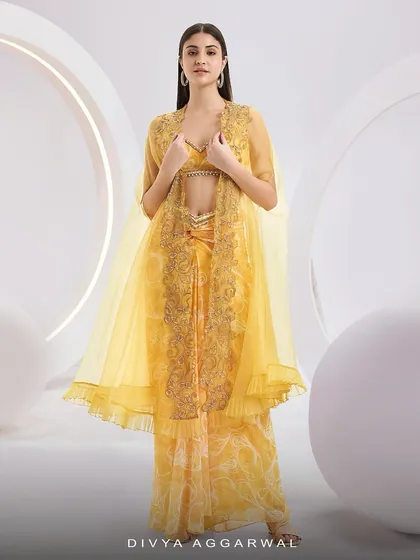 Our RUMI Cape Set in a vibrant yellow, featuring a knotted skirt, a blouse, and a sheer organza cape with abstract embroidery.