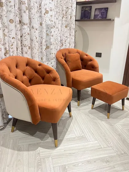 A set of two-tone accent chairs in a burnt orange velvet. The chairs feature a tufted back and a contrasting cream-colored exterior, creating a warm and inviting look.