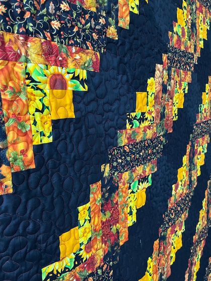 A detailed view of the Log Cabin blocks, showing the rich autumn-colored fabrics.