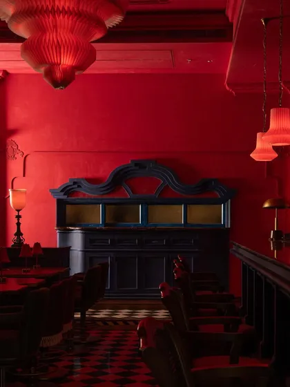 A detail of the bar area, where a deep blue cabinet provides a cool counterpoint to the surrounding red. The forms are a modern interpretation of classical Thai furniture.