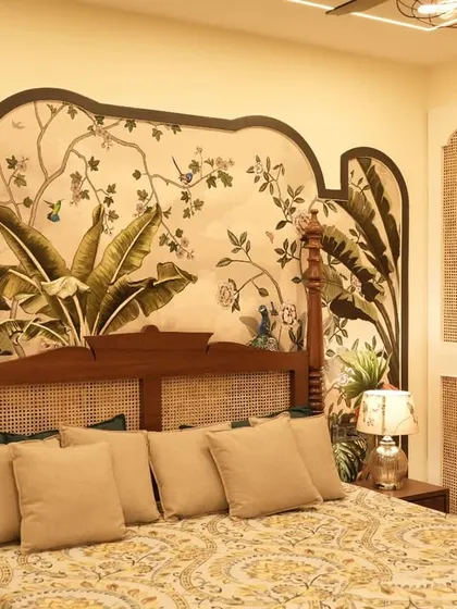 This bedroom showcases a beautiful blend of traditional and tropical design. The four-poster bed with cane detailing is set against a stunning, hand-painted tropical mural, creating a unique and artistic sanctuary.