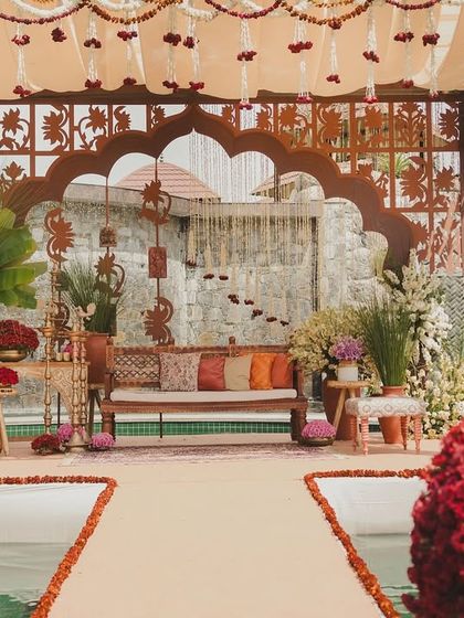 A beautiful seating area set over a pool, with a backdrop of a waterfall and intricate latticework.