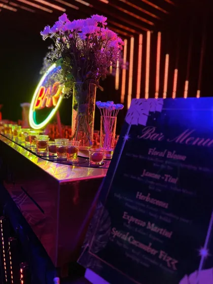 This neon bar setup features a custom menu with cocktails like 'Floral Bloom' and 'Espresso Martini', all served under dramatic LED lighting.