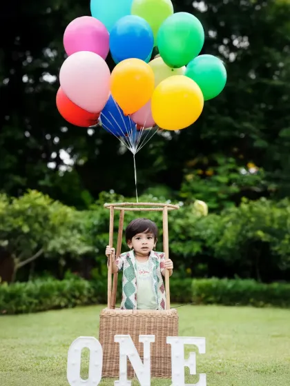 Up, up, and away! This hot-air balloon prop is a client favorite for first birthday shoots, creating a joyful and adventurous portrait against a beautiful outdoor backdrop in a Mumbai park.