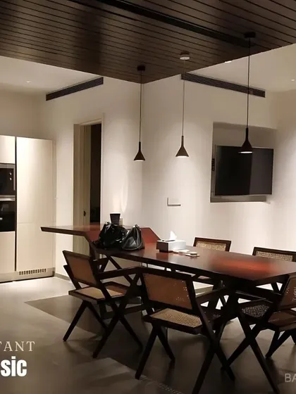 An instant classic. This dining space combines a dark wood table and Pierre Jeanneret-inspired chairs with a dark wood-paneled ceiling for a warm, sophisticated atmosphere.