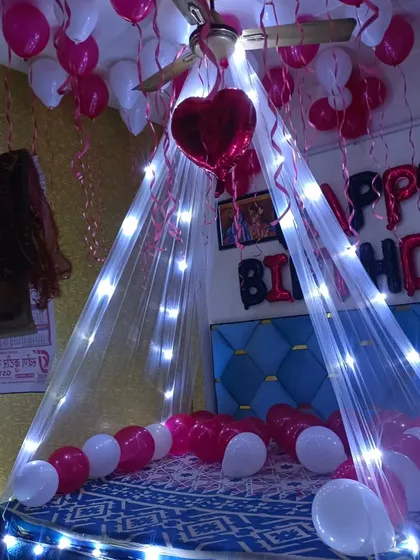 A birthday surprise canopy decoration in pink and white. The fairy lights on the canopy and heart-shaped foil balloon add a charming and delicate touch.